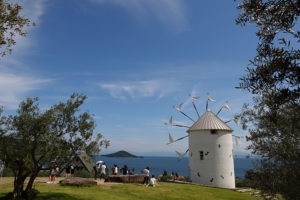 瀬戸内海の青い海とオリーブの木に囲まれたギリシャ風車