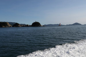 諏訪崎の白い魚霊塔と灯台が見える